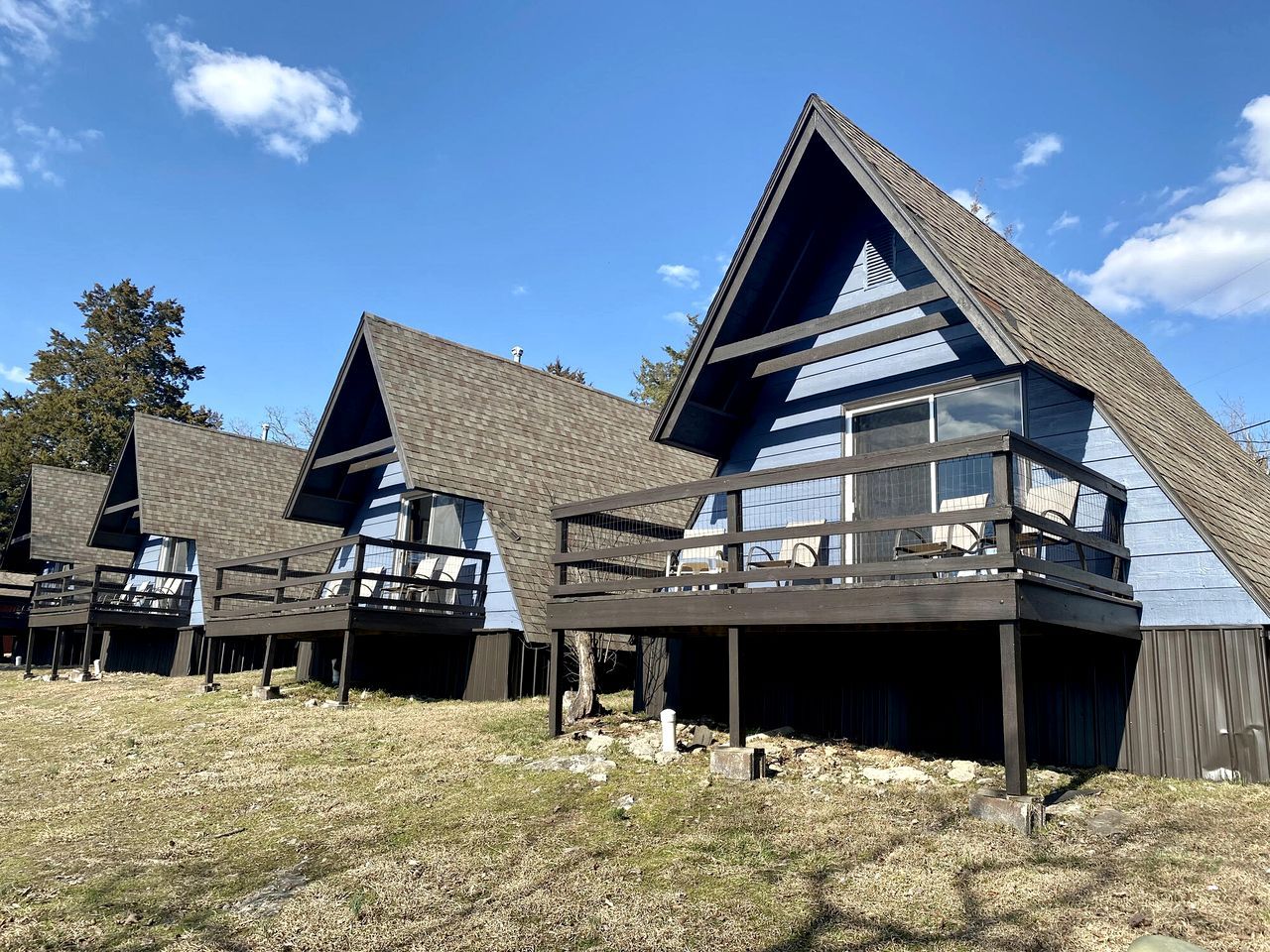 A row of modern cabins with sloped roofs and balconies, set on a grassy field.