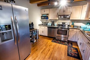 A kitchen with stainless steel appliances, wooden cabinets, and a wooden floor. - Glamping Retreat near Summersville Lake: Luxurious Cabin with a Hot Tub in Mt Nebo, WV (Mount Nebo)