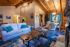 Ein gemütliches Wohnzimmer mit Sofa, Sessel, Couchtisch und Kamin.