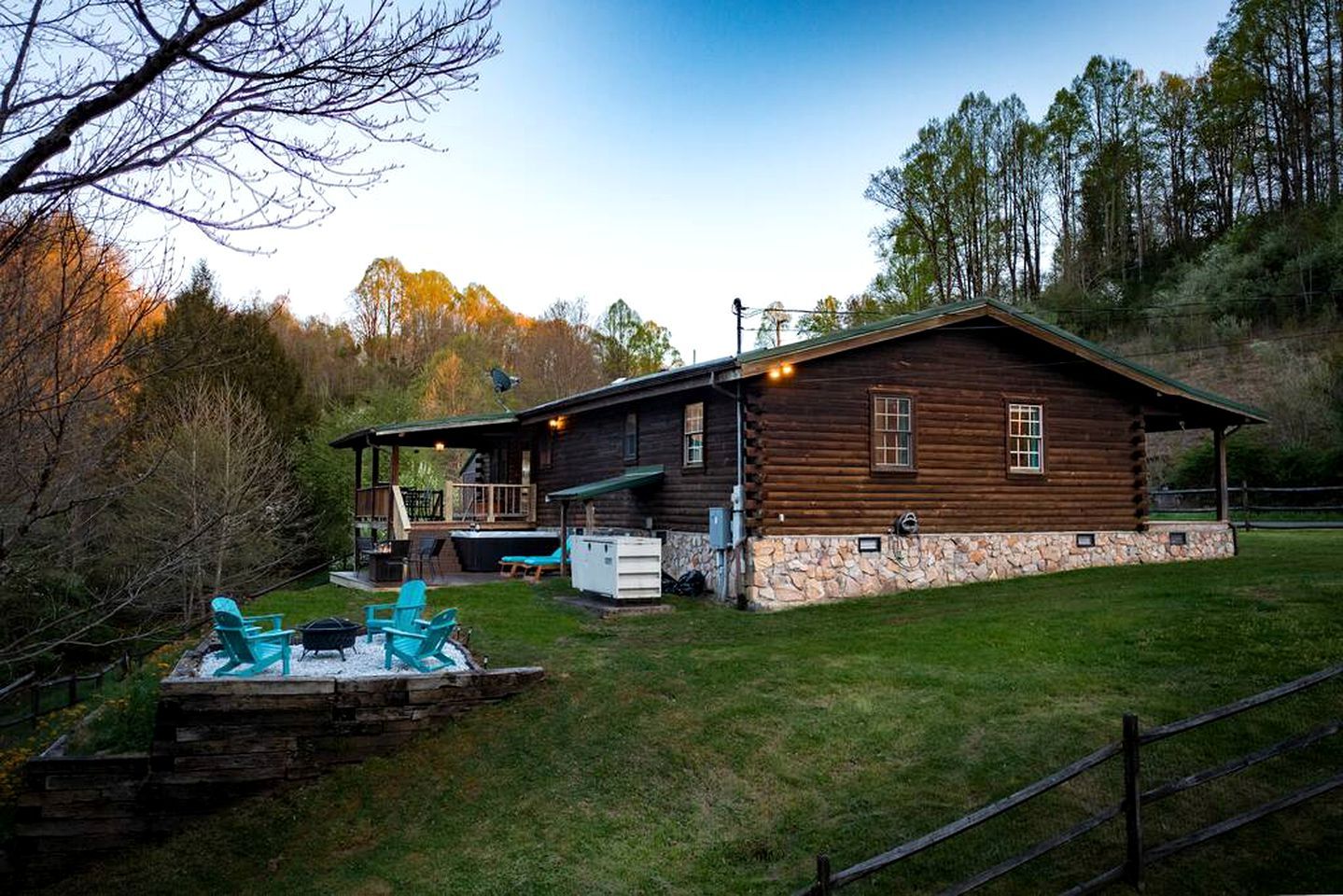 Eine Blockhütte mit Steinunterbau, einer Veranda mit Stühlen und einem Kamin aus Stein.