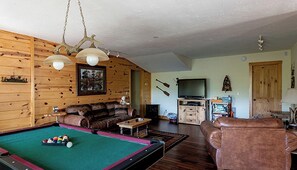 A cozy living room with a pool table, a leather sofa, and a television. - Dreamy Log Cabin with Spectacular Mountain Views in Topton, North Carolina (Topton)