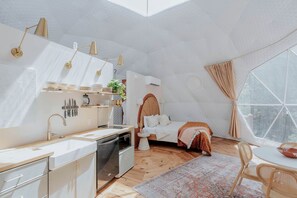 A compact, modern bedroom with a large window, a small kitchenette, and a cozy seating area. - Georgia's Trendy Family Escape: Dome with Private Hot Tub in Cherry Log (Cherry Log)