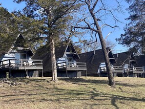 A row of cabins with sloped roofs, wooden decks, and a grassy area in front. - Glamping Getaway in an A-Frame, Ideal for a Nature Escape near Branson, Missouri (Branson)