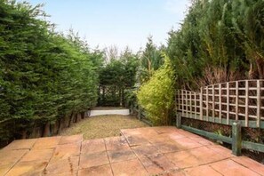 A paved pathway leading to a fenced garden area with dense greenery on both sides. - Toast Stays - Hydenside House (Consett)