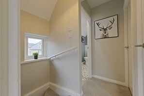 A hallway with a window, a door, and a framed deer antler picture. - Toast Stays - Hydenside House (Consett)
