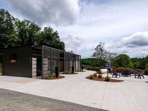 Un edificio con entrada cubierta, señal de accesibilidad para sillas de ruedas y mesas al aire libre.