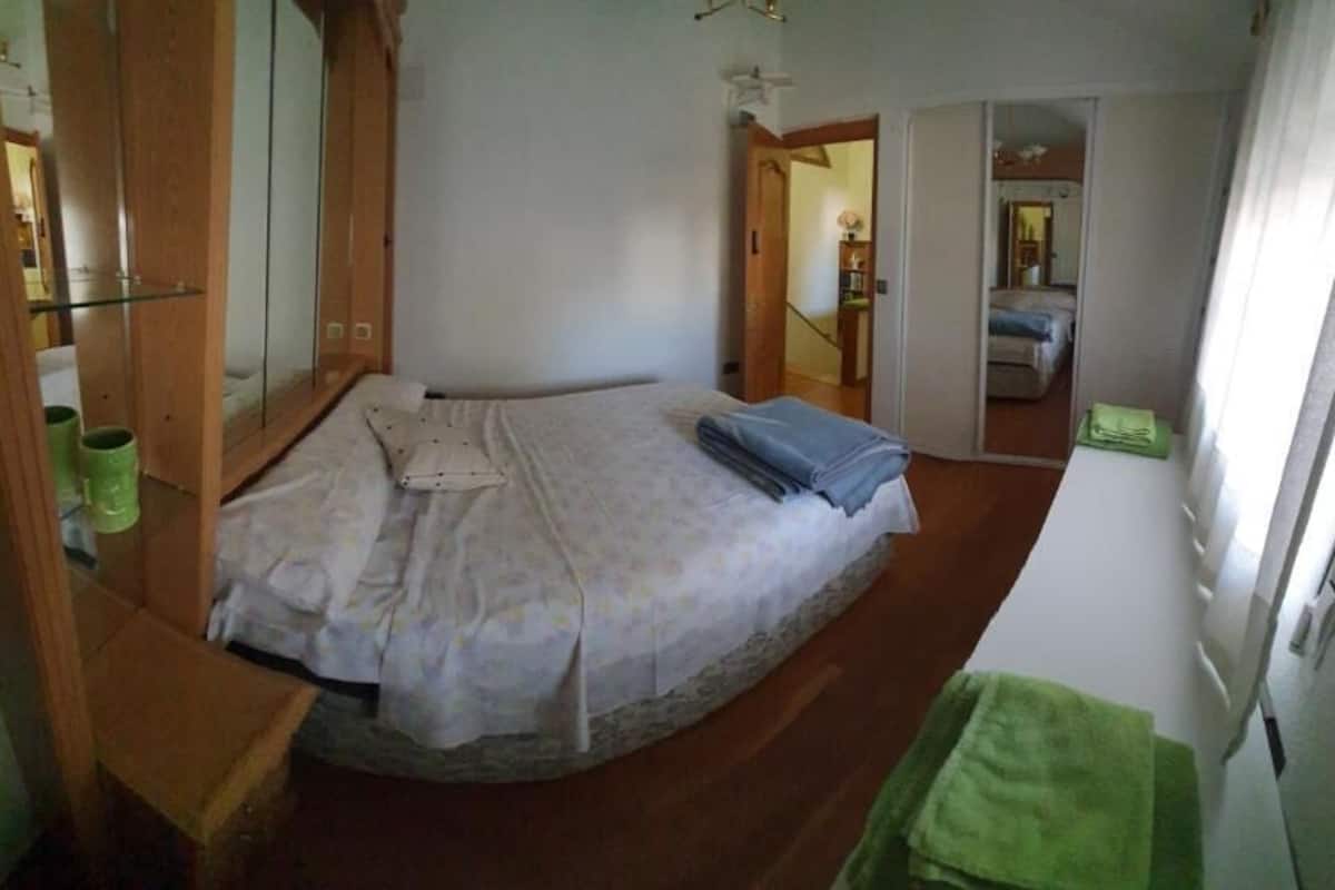 Ein Schlafzimmer mit einem Bett, einem Holzschrank, einem Spiegel und einem grünen Handtuch.