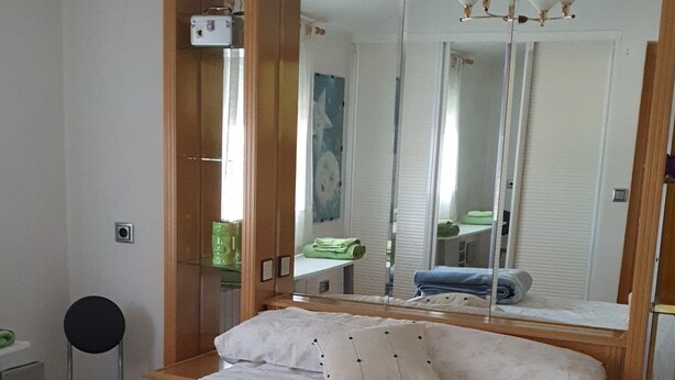 Un dormitorio con una cama grande, un espejo, una silla y un aparador.