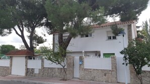 Un edificio de dos pisos con fachada de piedra, contraventanas blancas y techo de tejas.