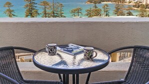 A round table with two chairs and two patterned mugs, overlooking a coastal view with trees and buildings. - Beachside Paradise - Ocean Views, Central Position (Sydney)