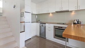 A modern kitchen with white cabinets, stainless steel appliances, and a wooden countertop. - Beachside Paradise - Ocean Views, Central Position (Sydney)