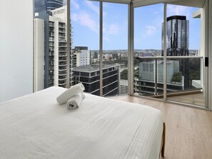 A hotel room with a large bed, a view of the city through floor-to-ceiling windows, and a modern building labeled "RIVERCITY" in the background. - Brisbane CBD Stay With Pool & Gym Access (Brisbane)