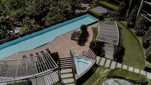 Area piscina sul tetto con una terrazza a forma di curva, poltrone da relax e una piccola vasca idromassaggio.