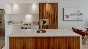 Una cucina moderna con isola centrale, elettrodomestici in acciaio inossidabile e una parete d'accento in legno.