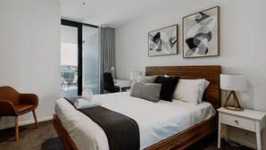 Camera d'albergo moderna con un letto grande, una scrivania, una sedia e due dipinti astratti alle pareti.