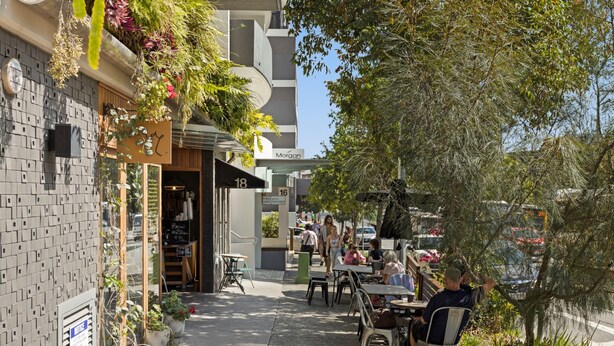 An outdoor cafe with tables and chairs, potted plants, and a building with a sign reading "Morgan". - Chic 2-bed Apartment & 5 Minutes Walk to Qpac (Brisbane)