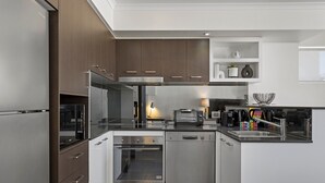 A modern kitchen with stainless steel appliances, white cabinetry, and a built-in oven. - Chic 2-bed Apartment & 5 Minutes Walk to Qpac (Brisbane)