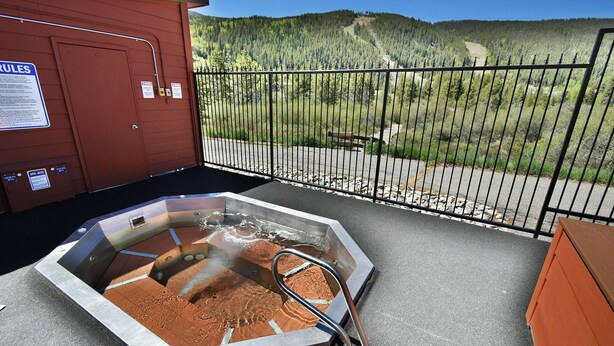 Ein Whirlpool auf einem Balkon mit Blick auf eine bewaldete Hügelkette.