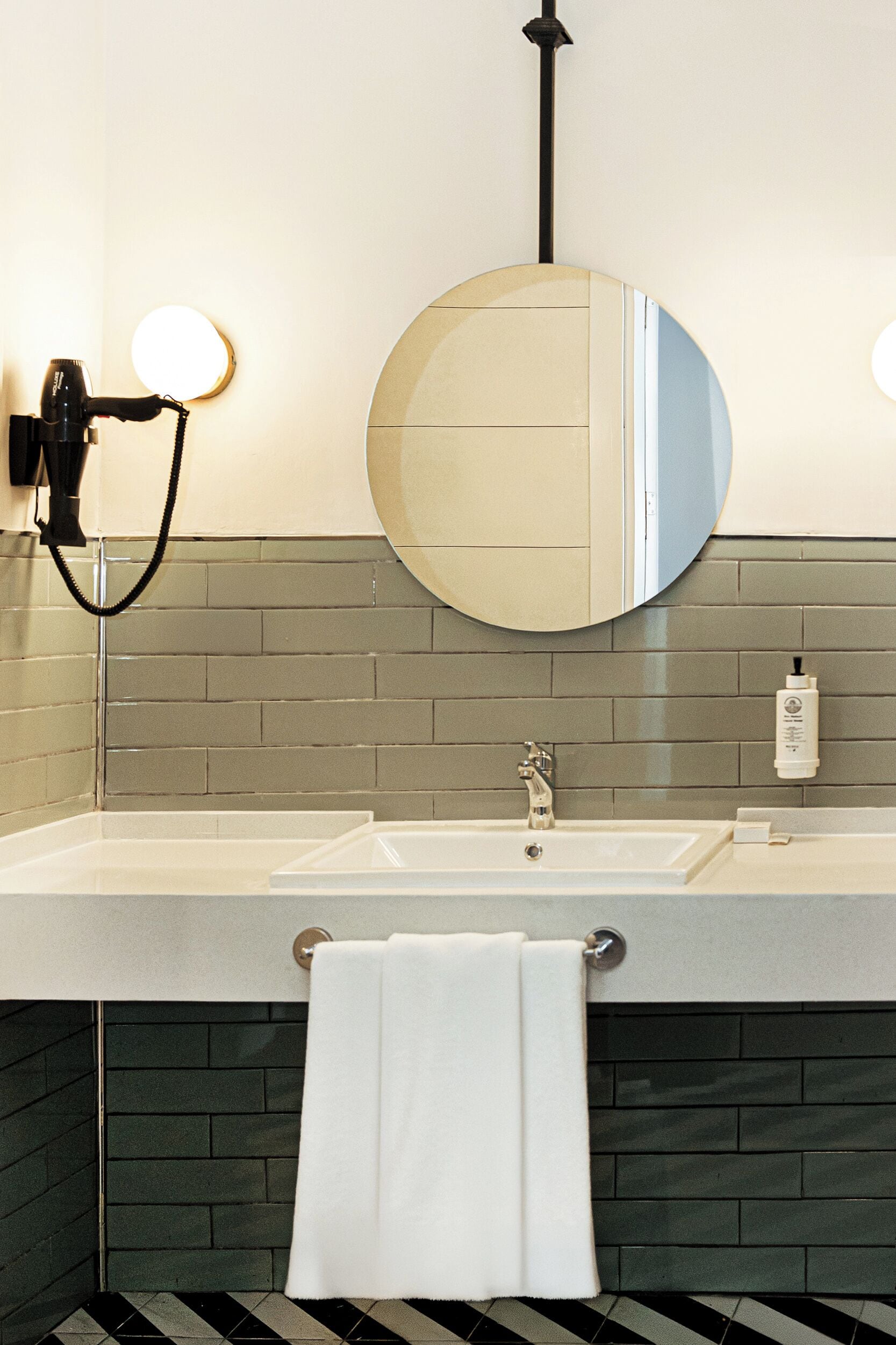 A bathroom with a large mirror, a hairdryer, and a towel rack.
