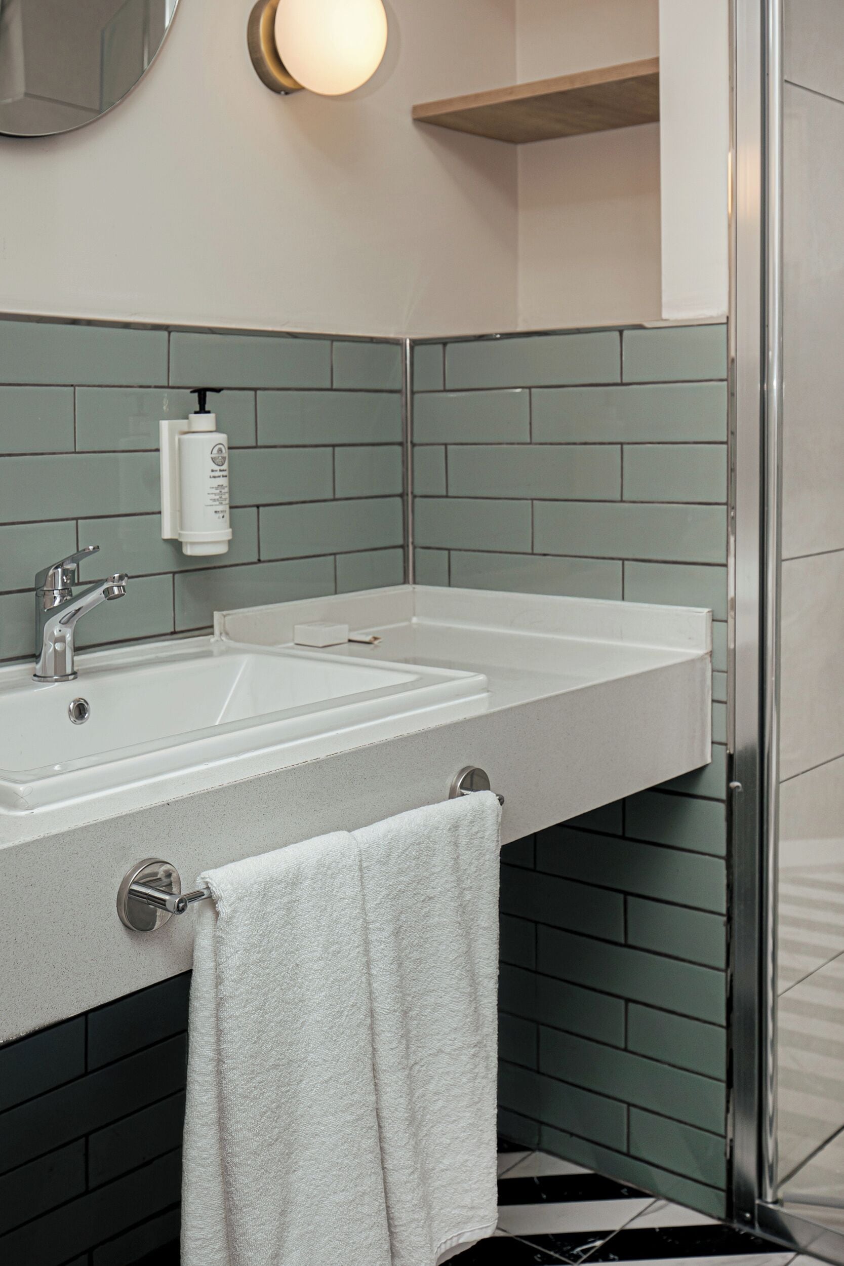 A bathroom with a white sink, a mirror, and a towel hanging on a rack.
