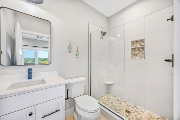 A bathroom with a white sink, toilet, and shower area. - Brand New Soundside Avon Home with Hot Tub and Water Views (Avon)