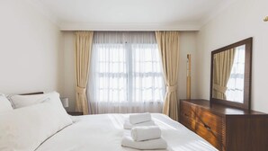 A hotel room with a bed, a dresser, a mirror, and a window with curtains. - Luxury 3BDR Home w Garden and Parking West London (Greater London)