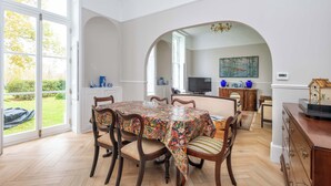 Ein Essbereich mit einem Tisch, der mit einer gemusterten Tischdecke bedeckt ist, umgeben von Holzkästen mit gepolsterten Sitzen.