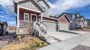A modern two-story house with a front porch, a garage, and a driveway.