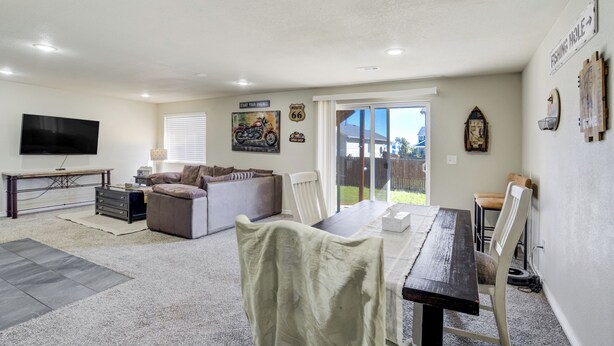 A spacious living area with a dining table, sofa, and a flat-screen TV mounted on the wall. - The Cozy Oak | Modern Basement Apartment (Fountain)