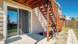 A house with a wooden deck, a sliding glass door, and a visible garage area. - The Cozy Oak | Modern Basement Apartment (Fountain)