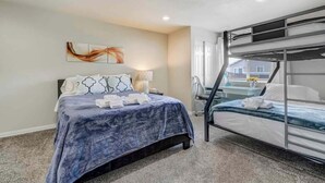 A hotel room with a bed, a bunk bed, a desk, and a window. - The Cozy Oak | Modern Basement Apartment (Fountain)