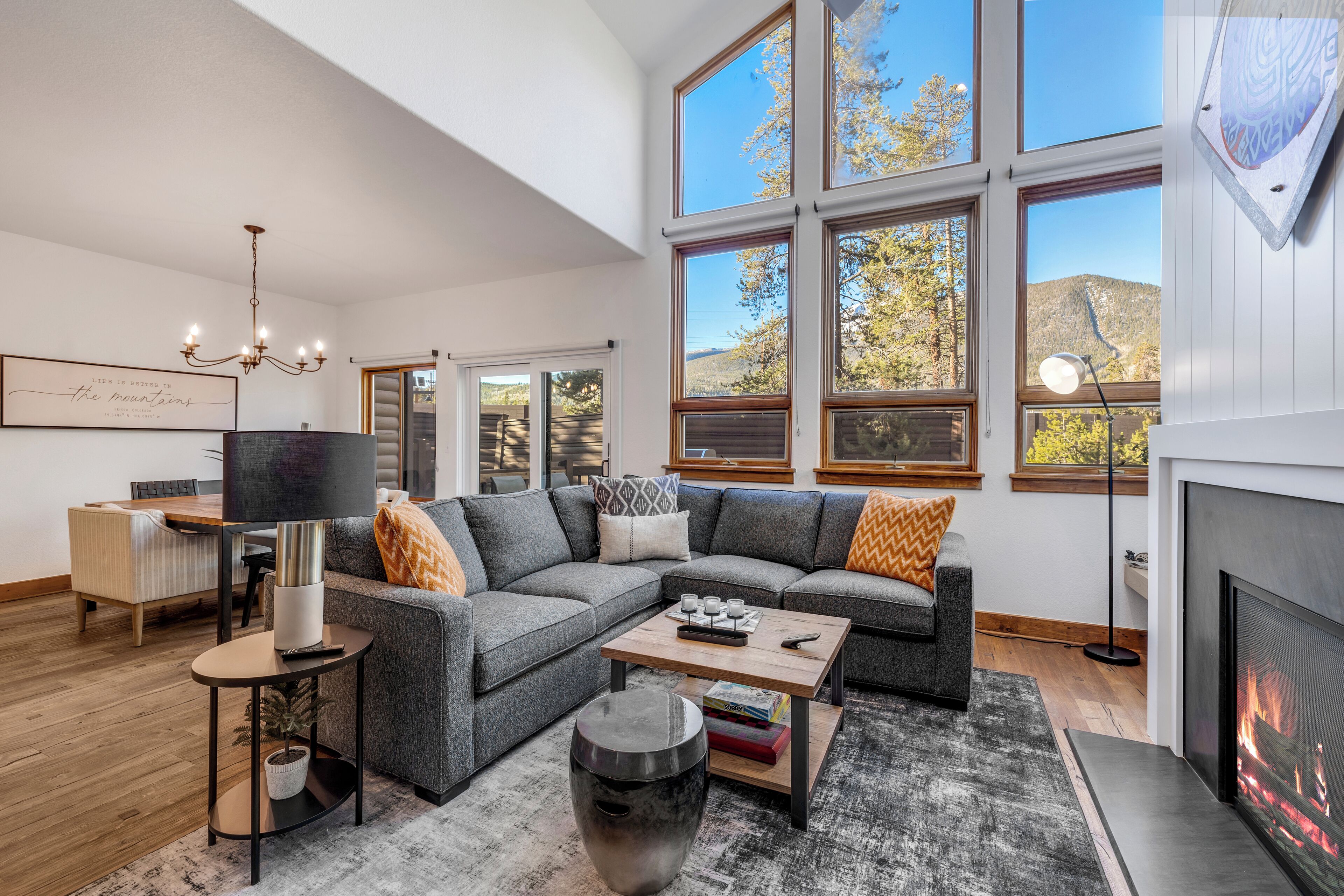 A modern living room with a sectional sofa, a fireplace, and large windows offering a mountain view.
