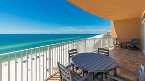 A balcony with a view of a beach and ocean, featuring a round table and two chairs. - Phoenix Orange Beach 806 4 Bedroom Condo (Orange Beach)