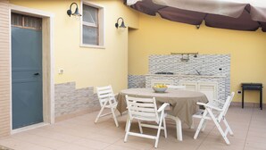 A patio with a table and chairs, a small kitchen area, and a door. - Monasteri Rural Holiday Home (Sicilia)