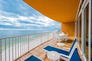 A balcony with a view of the sea, white chairs, and a table. - Phoenix Orange Beach 1006 4 Bedroom Condo (Orange Beach)