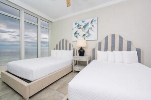Una habitación de hotel con dos camas, una mesita de noche, una lámpara y un cuadro de peces en la pared.