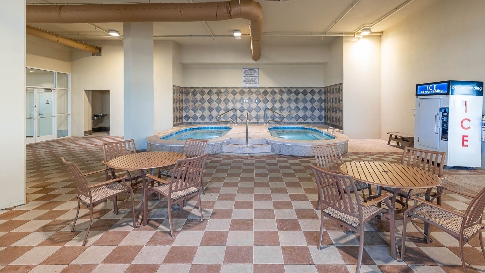 A pool area with checkered flooring, multiple seating arrangements, and a vending machine labeled "ICE".