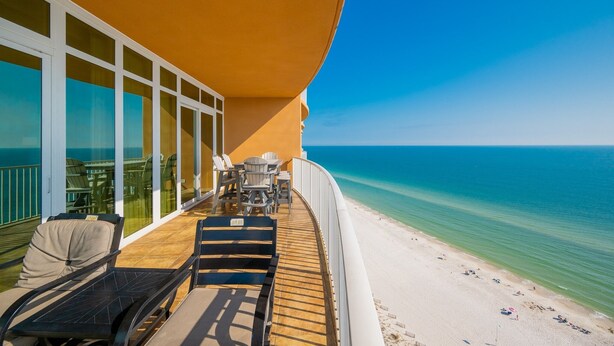 A balcony with outdoor seating, a view of the ocean, and a sandy beach. - Phoenix Orange Beach 1701 4 Bedroom Condo (Orange Beach)