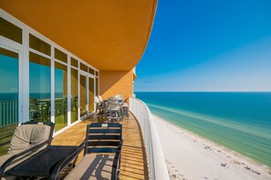 A balcony with outdoor seating, a view of the ocean, and a sandy beach. - Phoenix Orange Beach 1701 4 Bedroom Condo (Orange Beach)