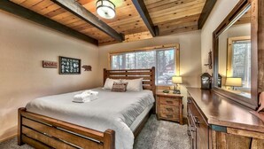 A bedroom with a wooden bed, a nightstand, a dresser, and a large mirror. - Coh0809 - Brule Haven 3 Bedroom Home (South Lake Tahoe)