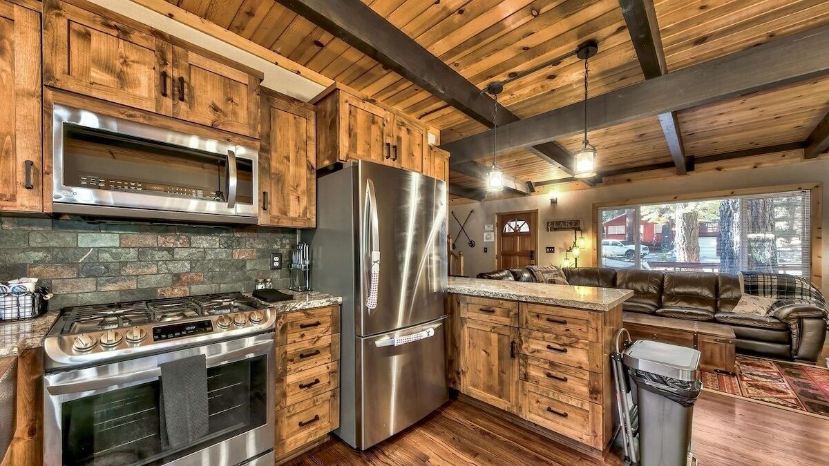 A kitchen with wooden cabinets, a stainless steel refrigerator, a microwave, and a gas stove.