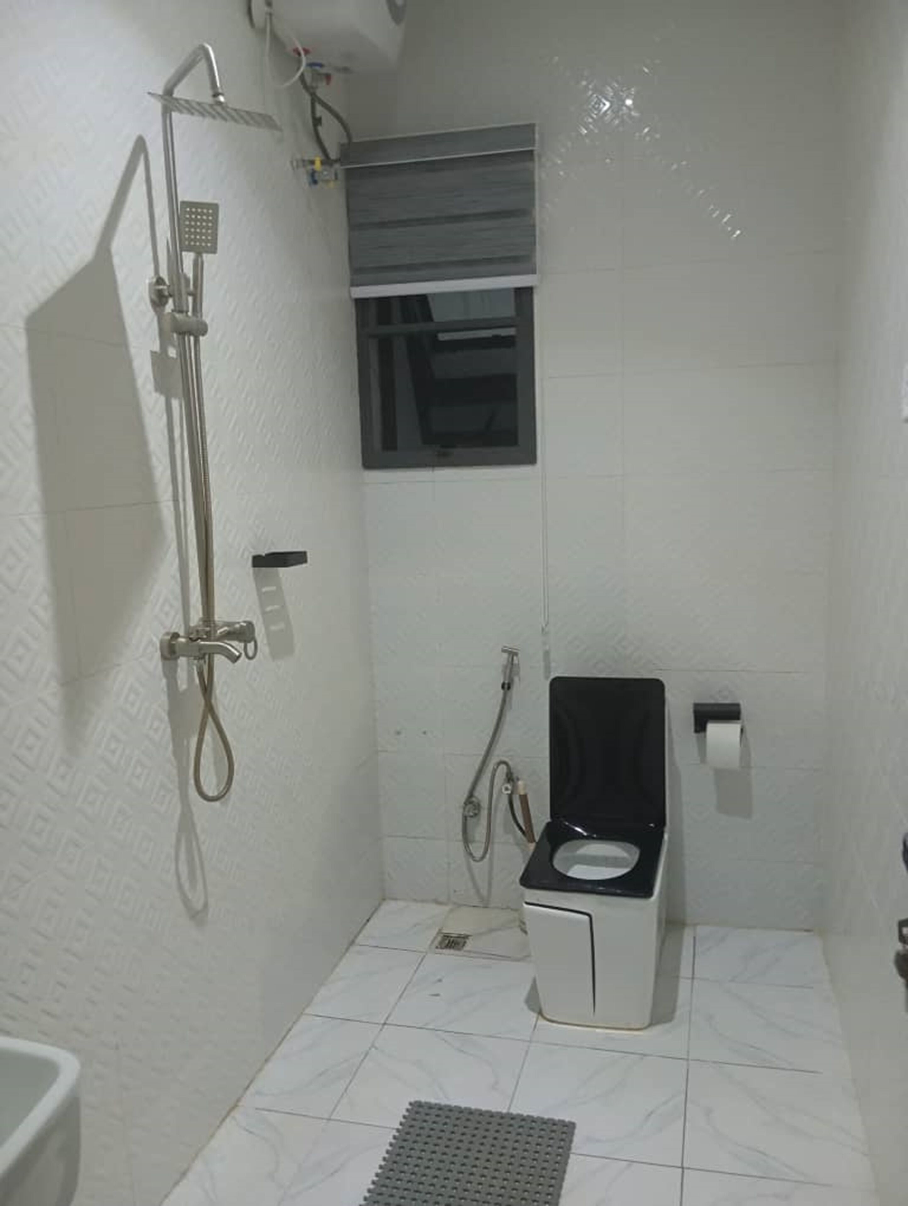 A small, compact bathroom with a shower, toilet, and a window.