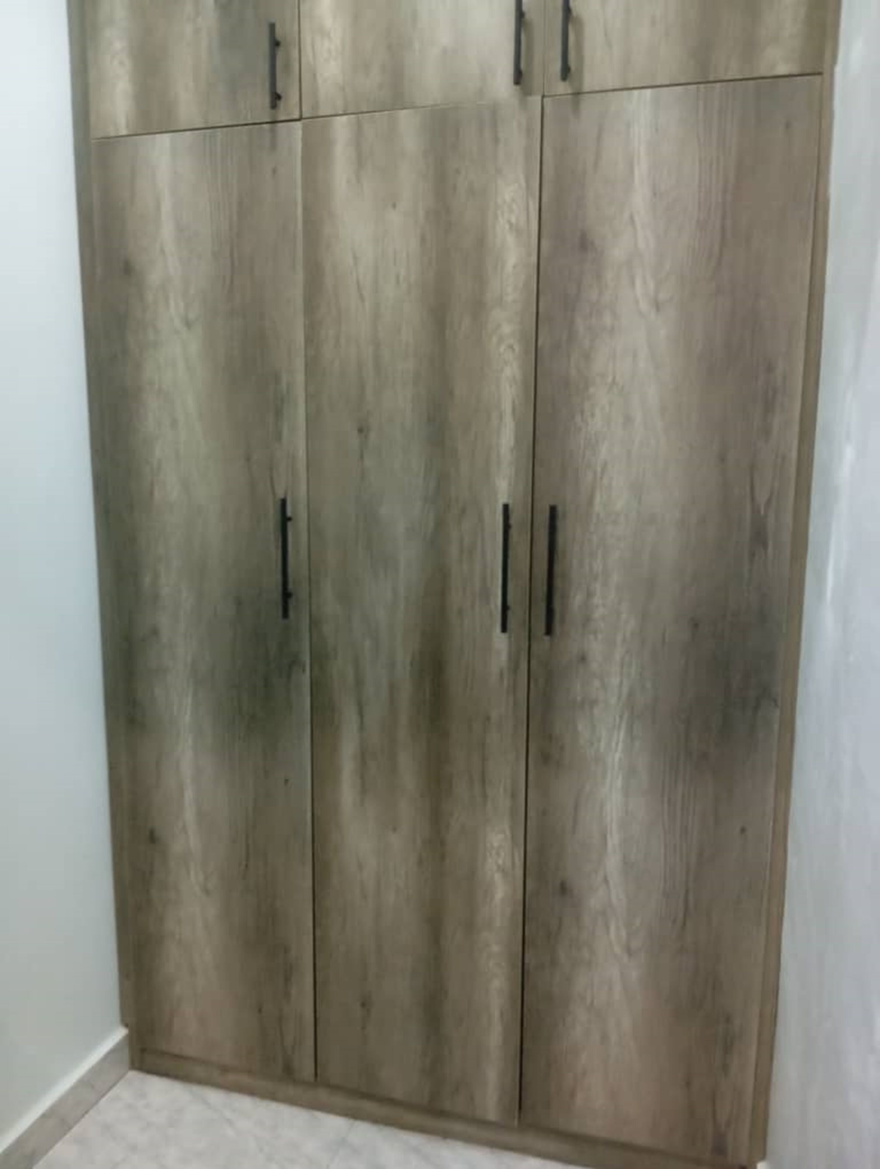 Ein großer Kleiderschrank mit zwei Türen und Griffen.