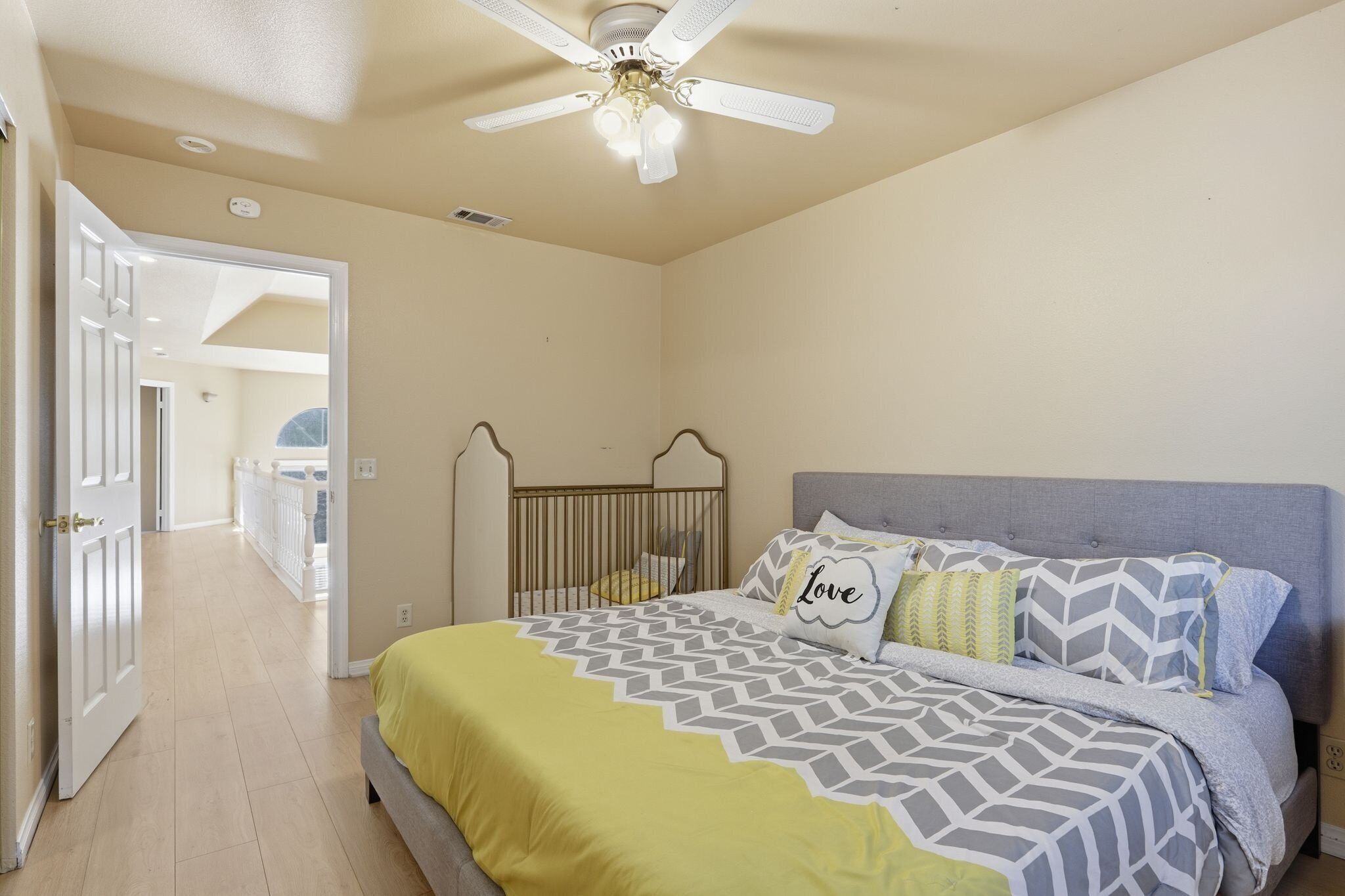 Un dormitorio con cama, ventilador de techo y vistas a un balcón.