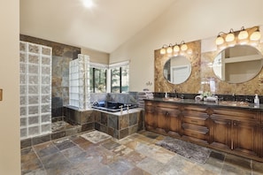 A spacious bathroom with a large bathtub, a vanity with a mirror, and a shower area with glass doors.