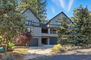 A two-story house with a stone facade, a balcony, and a driveway leading to a garage.