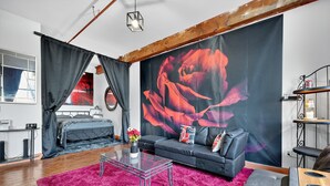 Una sala de estar moderna con un sofá grande, una mesa de centro y un cuadro llamativo de una rosa roja.