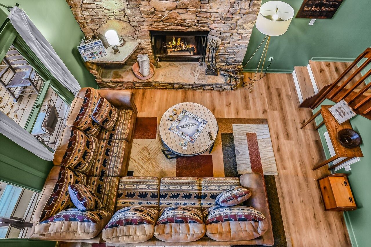 A cozy living room with a stone fireplace, a patterned sofa, and a round coffee table.