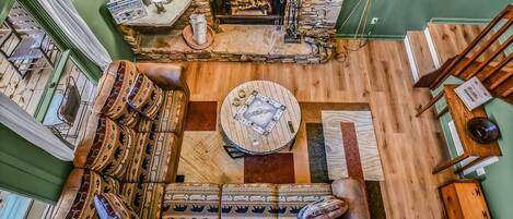 Una sala de estar acogedora con chimenea de piedra, un sofá estampado y una mesa de centro redonda.