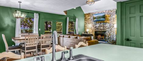 A kitchen with a stone wall, a fireplace, and a dining area with wooden furniture.